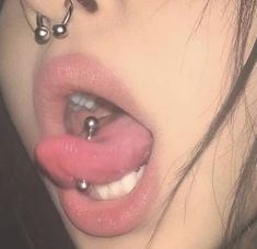 a close up of a person's nose with piercings on it and her tongue hanging out