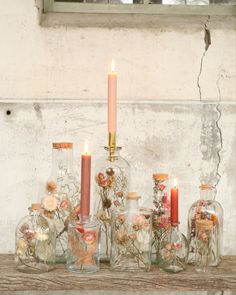 several glass jars filled with flowers and candles