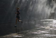 a woman running in the rain with water spraying from her head and feet behind her