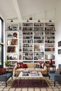 a living room filled with furniture and bookshelves next to a large glass window