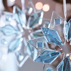 an ornament made out of glass is hanging from a string with lights in the background