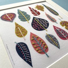 a close up of a framed artwork with many different colored leaves on the front and back of it