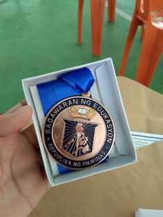 a person is holding up a medal in their hand and it has a blue ribbon