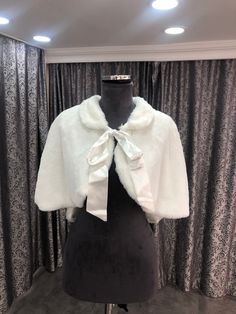 a mannequin wearing a white jacket with a bow at the neck and sleeves