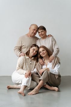 an older man and two younger women sitting on the floor with their arms around each other