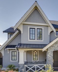 a gray house with white trim and black shutters on the front door is shown