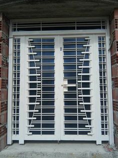 an open white door with metal bars on the side and brick wall behind it, in front of a building