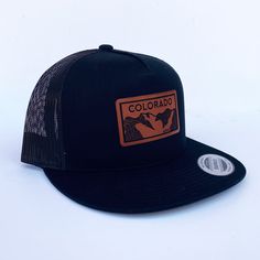 Colorado Elevation mountains faux leather patch in rawhide. Available in silver gray or black. Flat bill cotton twill front. Mesh back with adjustable snapback Black Hat With Logo Patch For Outdoor Activities, Brown Snapback Hat With Flat Bill For Outdoor Activities, Brown Snapback Hat With Flat Bill For Outdoor, Adjustable Trucker Hat Made In Usa For Outdoor, Urban Style Hats With Logo Patch For Outdoor, Outdoor Snapback Hat With Flat Bill Made In Usa, Flat Bill Hat With Logo Patch For Outdoor Activities, Urban Hats With Logo Patch And Flat Bill, Urban Snapback Hat With Flat Bill For Outdoor Activities