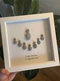 a person holding up a white frame with rocks in it and the words, it takes a big heart to shape little jewels