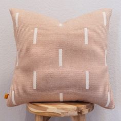 a brown and white pillow sitting on top of a wooden stool next to a wall