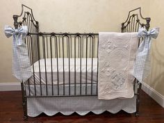 a baby crib with blue and white bedding on the floor next to a wall