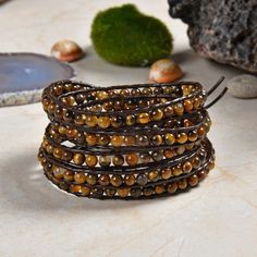 "Features: Length:33\" / 34\" / 35\"L. 32\" 5 wrap bracelet; dark brown leather. 4MM polished tiger's eye round beads. The bracelet is carefully handcrafted using high-quality thread that does not stretch and resists fraying. Each bead is stitched with multiple strings of threads for added durability. This unique wrap bracelet is designed to wrap around the wrist up to five times. Get the perfect custom fit on your wrist. Then trim off the extra leather.  The size of the round shape silver butto Brown Spiritual Wrap Bracelet With Natural Stones, Spiritual Brown Wrap Bracelet With Natural Stones, Brown Hand Wrapped Wrap Bracelet As Gift, Brown Hand Wrapped Wrap Bracelet Gift, Healing Brown Wrap Bracelet With Natural Stones, Spiritual Brown Wrap Bracelet For Healing, Adjustable Brown Spiritual Wrap Bracelet, Brown Hand Wrapped Spiritual Wrap Bracelet, Spiritual Hand-wrapped Brown Wrap Bracelet