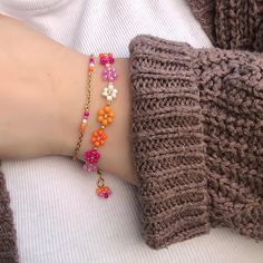 a woman's arm with two bracelets on top of it and flowers in the middle