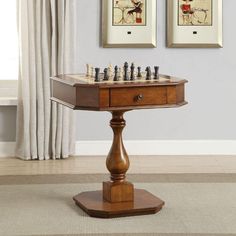 a chess set sitting on top of a wooden table in front of two framed pictures