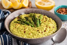 asparagus dip in a bowl with lemons and other food items around it