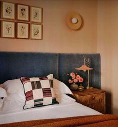 a bed with white sheets and pillows next to a wooden dresser topped with flowers on top of it