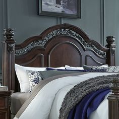 a bed with a wooden headboard and foot board in a room that has blue walls