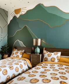 two beds in a room with mountains painted on the wall