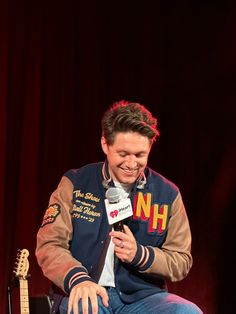 a man sitting in a chair holding a microphone and talking to someone on the mic