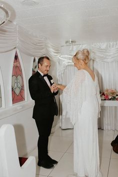 a man and woman standing next to each other in front of a table with white cloths