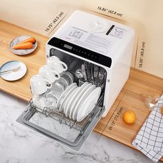 an open dishwasher sitting on top of a counter next to plates and utensils