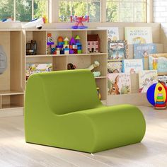 a green chair sitting in front of a book shelf filled with children's books