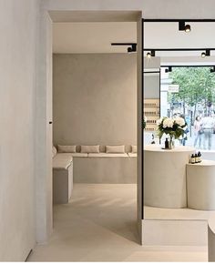 the interior of a store with white furniture and flowers in vases next to large mirrors