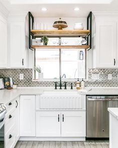 a kitchen with white cabinets and stainless steel dishwasher in the center, along with an open window over the sink