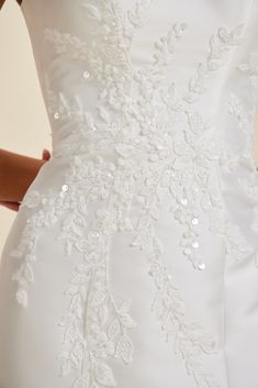 the back of a woman's wedding dress with sequins and flowers on it