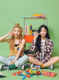 two young women sitting on the floor with books and toys in front of their faces