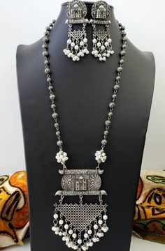 German silver Indian pendant necklace with Taj Mahal in 3D, and a beautiful geometric pendant with faux pearl dangling ghungroo. In a soft grey color with the patina of a vintage piece. Realistic faux pearls Excellent quality and craftsmanship. Necklace measures 12 inch drop. Pendant measures 4.5 inches by 3 inches. View more necklaces here: https://www.etsy.com/shop/BoutiqueByMaryam?section_id=21694658 Be sure to visit the rest of my shop here: https://www.etsy.com/shop/boutiquebymaryam Gift Silver Temple Necklace With Pearl Chain, Silver Dangle Temple Jewelry Necklace, Traditional White Necklace With Oxidized Finish, Traditional Silver Jewelry With Pearl Pendant, Traditional White Oxidized Finish Necklace, Traditional White Necklaces With Oxidized Finish, Silver Temple Jewelry Necklace With Pearl Pendant, Silver Necklace With Pearl Pendant In Temple Style, Traditional White Metal Necklace