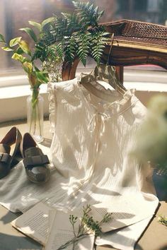 a pair of shoes sitting on top of an open book next to a white shirt