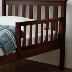 a wooden bed frame with white pillows and blue blankets on it's headboard