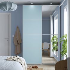 a bedroom scene with focus on the bed and closet doors that have been painted light blue