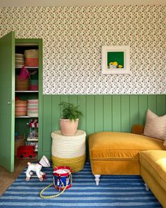 a living room with green painted walls and colorful rugs on the floor next to a yellow couch