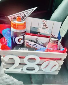 a baseball themed basket in the back seat of a car with sports items inside it