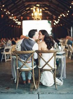 a bride and groom sitting at a table in a barn