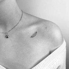 a black and white photo of a woman's chest with an angel wing tattoo on it