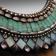 a close up of a necklace on a wooden table with a mirror in the background