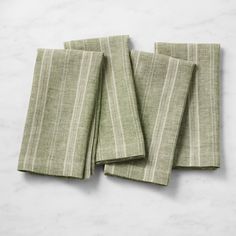 four green striped napkins sitting on top of a white countertop next to each other