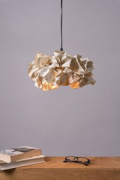 a lamp that is made out of old book pages hanging from a light fixture over a table