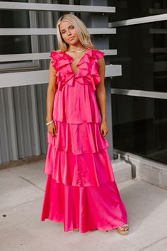 - Be ready to feel fabulous in this stunning dress!
 - Fully lined material with a satin finish
 - A ruffled deep-v neckline
 - An open back with tie detail
 - Short flutter sleeves
 - A waistline with an elastic back 
 - A flowy tiered silhouette that ends in a maxi length hemline Pink V-neck Ruffle Dress For Party, Chic Pink V-neck Ruffle Dress, Pink V-neck Maxi Dress With Ruffles, V-neck Ruffled Maxi Dress For Prom, Glamorous Satin Maxi Dress For Spring, Pink Satin V-neck Dress For Night Out, Satin Tiered Dress With Ruffles, Tiered Satin Dress With Ruffles, Pink V-neck Satin Dress For Night Out