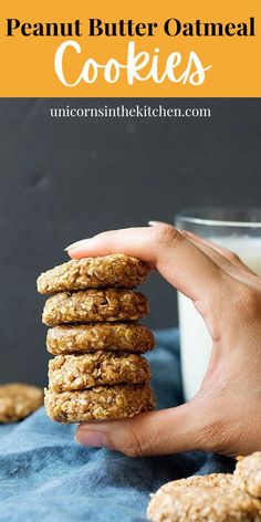 a hand holding a stack of peanut butter oatmeal cookies next to a glass of milk