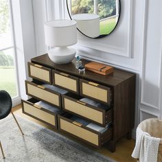 a dresser with drawers and a mirror on the wall in a living room next to a chair