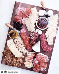 an assortment of meats and cheeses on a cutting board