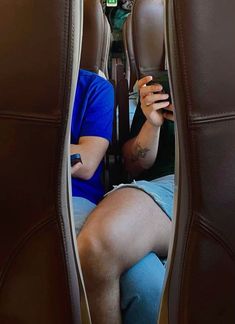 a man sitting in the seat of an airplane looking at his cell phone