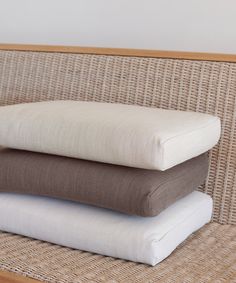 three pillows stacked on top of each other in front of a wicker chair cushion