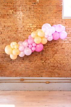 balloons are arranged in the shape of a wave on a brick wall with wood flooring