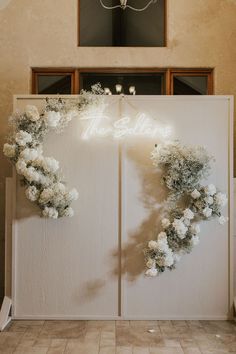 two white doors decorated with flowers and greenery in front of a chandelier