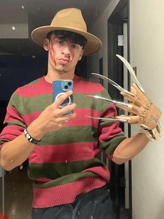 a man wearing a hat and holding a cell phone with his hands in the shape of claws